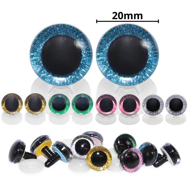 May include: A collection of colorful craft eyes, including pairs in blue, gold, green, pink, and silver. The blue eyes are 20mm in diameter. The eyes have black pupils and are designed for various craft projects, such as stuffed animals and dolls.