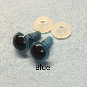 May include: Two blue plastic safety eyes with black pupils and metal shanks. The eyes are on a light blue surface with two white plastic washers.