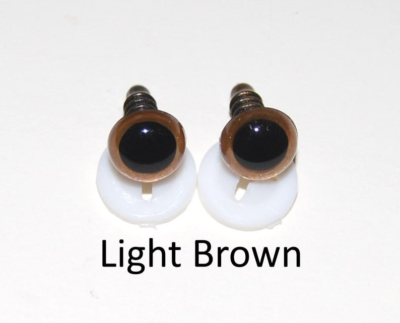 May include: Two light brown plastic safety eyes with black pupils, mounted on white plastic bases. The eyes are for craft projects.