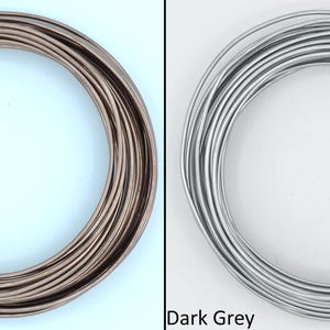 May include: Two spools of wire, one in sienna brown and one in dark grey. The wire is coiled neatly.