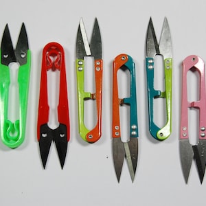 May include: Seven pairs of small scissors with different coloured handles. The handles are green, red, green, orange, blue, green, and pink.