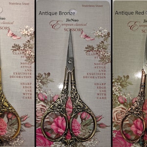 Könnte beinhalten: Drei Paare dekorativer Scheren mit verzierten Griffen. Die Scheren sind in Antikgold, Antikbronze und Antikrotkupfer gehalten. Die Verpackung zeigt ein Blumenmuster und den Text "JieNuo european classical SCISSORS".
