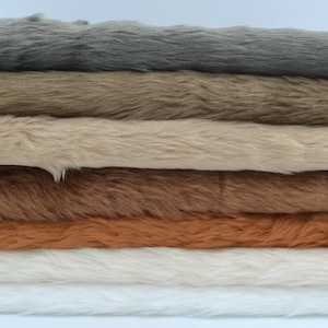 May include: Six different colours of faux fur fabric stacked on top of each other. The colours are grey, brown, beige, brown, orange, and white.