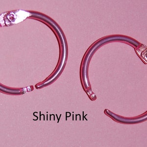 May include: Two shiny pink metal binder rings. The rings are open and ready to be used.