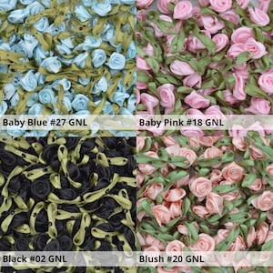 May include: Assortment of small fabric flower embellishments in four colors: baby blue, baby pink, black, and blush. Each flower is made of satin ribbon and has a green leaf stem.