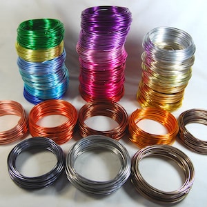 May include: A collection of colorful aluminum wire spools in various colors, including green, purple, pink, gold, silver, copper, and bronze. The wire is arranged in neat stacks and is ready for crafting projects.