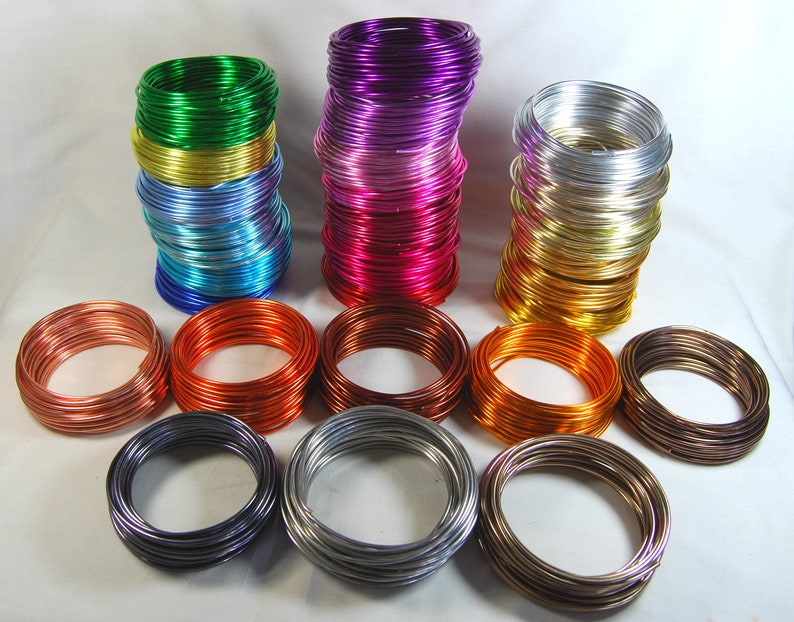 May include: A collection of colorful aluminum wire spools in various colors, including green, purple, pink, gold, silver, copper, and bronze. The wire is arranged in neat stacks and is ready for crafting projects.