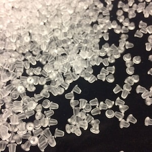 Peut inclure: Un grand tas de dos d'oreille en plastique transparent. Les dos sont petits et ronds avec un petit trou au centre.