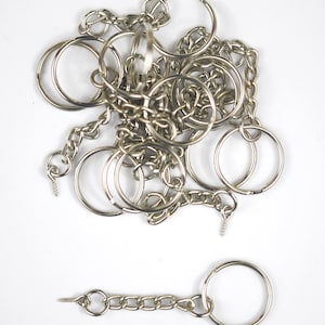 Peut inclure: Un tas de porte-clés et de chaînes argentés, certains avec des anneaux fendus, et un seul porte-clés avec une chaîne.