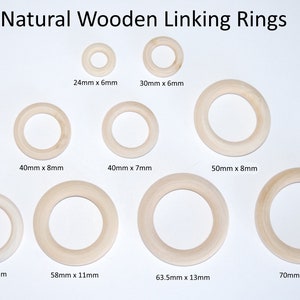 May include: Nine natural wooden linking rings of varying sizes. The rings are arranged in three rows. The rings are all made of unfinished wood and have a smooth surface. The rings are labelled with their dimensions in millimetres.
