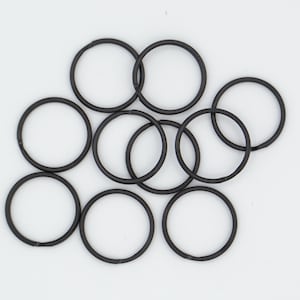 May include: Ten black metal key rings are displayed against a white backdrop. Each ring is circular, with some overlapping. The key rings are made of a dark, matte metal, suitable for keys or other small items.