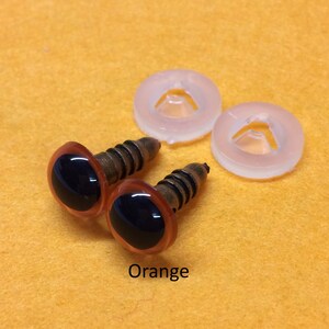 May include: Two orange plastic safety eyes with black pupils and metal screw backs. The eyes are accompanied by two clear plastic washers.