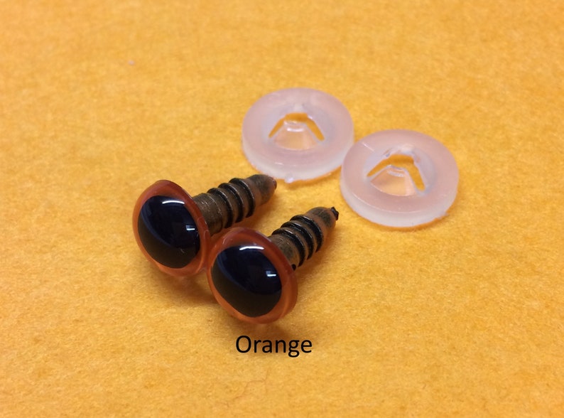 May include: Two orange plastic safety eyes with black pupils and metal screw backs. The eyes are accompanied by two clear plastic washers.