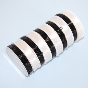 May include: A stack of spools of black elastic cord, each spool is wrapped in white plastic.