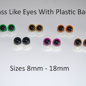 May include: Assortment of glass-like plastic eyes in various colors, including green, gold, orange, blue, dark blue, black, pink, and brown. The eyes are 8mm to 18mm in size and have plastic backs.
