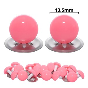 Puede incluir: Dos grandes ojos de seguridad esf&eacute;ricos de color rosa con arandelas met&aacute;licas plateadas, cada uno de 13,5 mm de di&aacute;metro. Debajo, una colecci&oacute;n de ojos de seguridad rosas m&aacute;s peque&ntilde;os con postes de pl&aacute;stico blanco y arandelas plateadas.