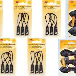 May include: A package of three black zipper pulls with a white rectangular tag that says "Cool" in pink, blue, and green lettering. The package is labeled "Reißverschluss-Anhänger" and has a yellow background.