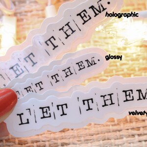 a hand holding a pair of white stickers