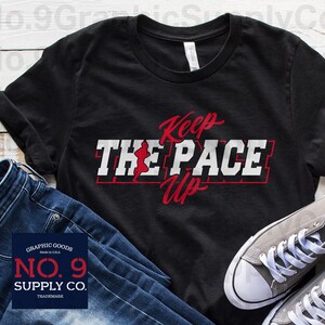 May include: Black t-shirt with white text that reads "Keep The Pace Up" in a red and white graphic design. The graphic includes a stylized running figure. The shirt is from No. 9 Supply Co. and has a graphic goods trademark.