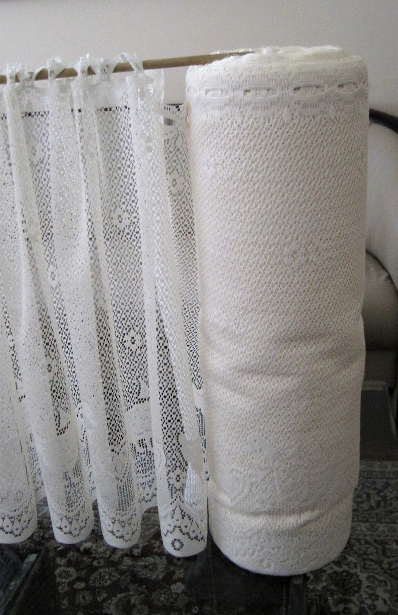 Pu&ograve; includere: Un rotolo di pizzo bianco con un motivo delicato. Il tessuto &egrave; arrotolato e legato con un nastro bianco. Il pizzo &egrave; perfetto per l'artigianato, la cucitura e la decorazione.