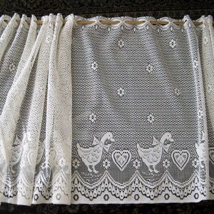 Pu&ograve; includere: Tenda di pizzo bianco con un motivo di anatre e cuori. La tenda &egrave; realizzata in un tessuto delicato e trasparente e ha un bordo a festoni.