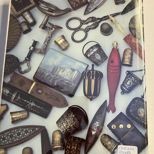 May include: A collection of antique sewing tools and accessories, including thimbles, scissors, needle cases, and decorative items. The items are in various materials, such as metal, wood, and leather, and feature intricate designs and embellishments. The items are arranged on a light-colored surface.