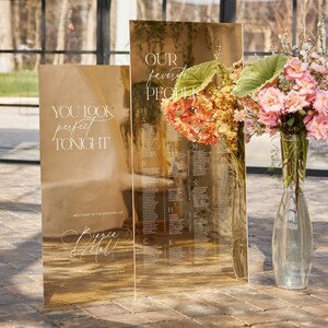 May include: Gold mirrored wedding seating chart with the text "YOU LOOK perfect TONIGHT" and "OUR favorite PEOPLE". The chart includes a list of names and is decorated with flowers. The wedding is in Draper, Utah.