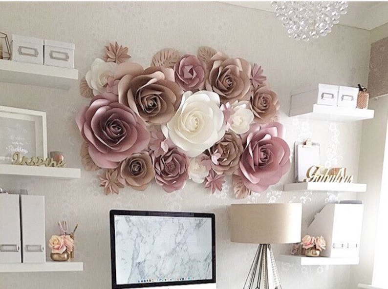 K&ouml;nnte beinhalten: Eine Wand, die mit gro&szlig;en Papierblumen in Rosat&ouml;nen und Cremefarben dekoriert ist. Die Blumen sind in einer Gruppe angeordnet und schaffen einen sch&ouml;nen und eleganten Hintergrund.