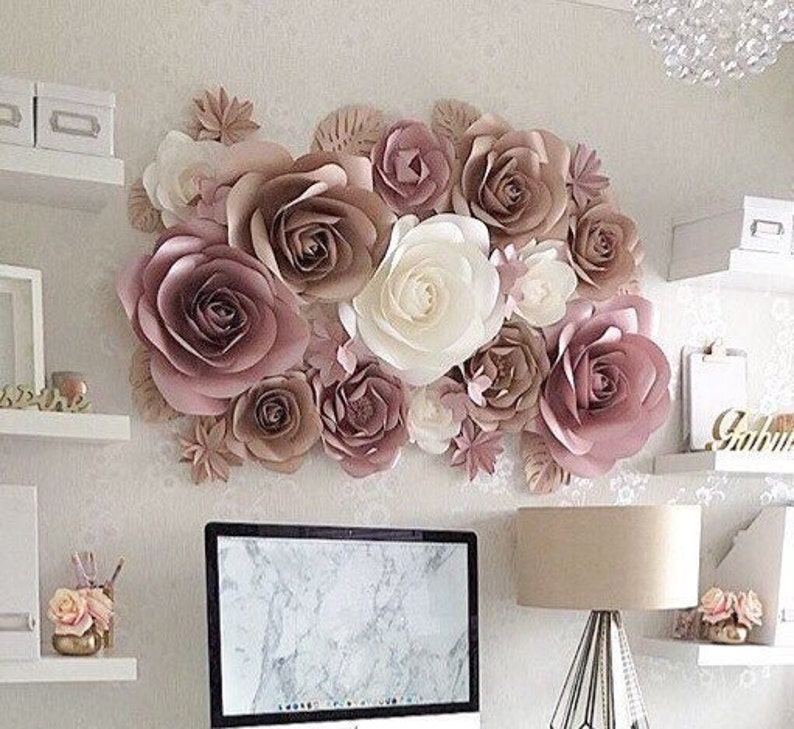 May include: A wall decor made of large paper flowers in shades of pink and white. The flowers are arranged in a cluster and create a beautiful and elegant display.