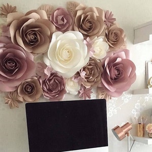 K&ouml;nnte beinhalten: Eine Wand, die mit gro&szlig;en Papierblumen in den Farben Blush-Rosa, Beige und Creme dekoriert ist. Die Blumen sind in einer Gruppe angeordnet und schaffen eine romantische und elegante Atmosph&auml;re.