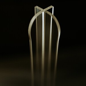 May include: A clear acrylic sculpture with a geometric design. The sculpture is made of multiple pieces of acrylic that are joined together to create a three-dimensional shape.