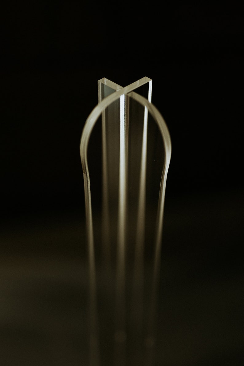 May include: A clear acrylic sculpture with a geometric design. The sculpture is made of multiple pieces of acrylic that are joined together to create a three-dimensional shape.