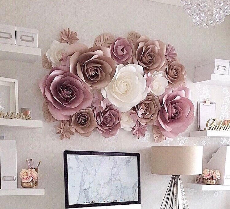 May include: A wall decor made of large paper flowers in shades of pink, brown, and white. The flowers are arranged in a cluster and create a beautiful and elegant statement piece.