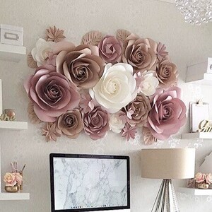 K&ouml;nnte beinhalten: Eine Wanddekoration aus gro&szlig;en Papierblumen in Rosa- und Wei&szlig;t&ouml;nen. Die Blumen sind in einer Gruppe angeordnet und schaffen ein wundersch&ouml;nes und elegantes Dekor.