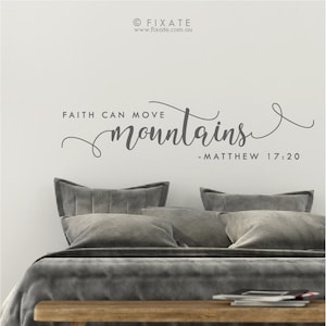 May include: A grey wall with a cursive quote that reads "Faith can move mountains - Matthew 17:20". The quote is above a grey bed with grey pillows.