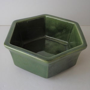 May include: A green hexagonal ceramic planter with a glossy finish.