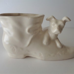 May include: White ceramic planter shaped like a boot with a small dog peeking out of the top.