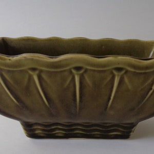 May include: A green ceramic planter with a scalloped rim and a fluted design. The planter has a square base.