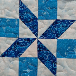 May include: A blue and white quilt with a starburst pattern. The quilt is made of different fabrics with various blue patterns and white snowflakes.