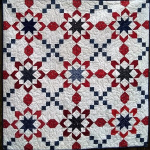 May include: A red, white, and blue quilt with a star pattern. The quilt is made of squares and has a white background with red and blue stars.