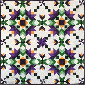 May include: A quilt with a geometric pattern in shades of purple, green, orange, and white. The quilt is made up of squares and triangles, and the pattern is repeated throughout the quilt.