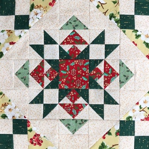 May include: A quilt block with a star design in the center. The star is made of red, green, and white fabric. The background of the block is a cream color with a subtle floral pattern.