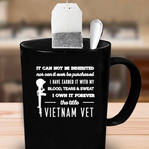 May include: Black ceramic mug with a white graphic and text. The text reads "IT CAN NOT BE INHERITED nor can it ever be purchased I HAVE EARNED IT WITH MY BLOOD, TEARS & SWEAT I OWN IT FOREVER the title VIETNAM VET."