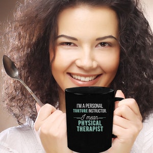May include: Black coffee mug with white text that reads "I'm a personal torture instructor. I mean physical therapist."