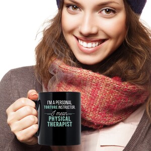 May include: Black coffee mug with white text that reads "I'm a personal torture instructor. I mean physical therapist."