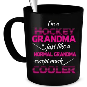 Puede incluir: Taza de caf&eacute; negra con un dise&ntilde;o rosa y blanco que dice "Soy una abuela de hockey como una abuela normal, excepto mucho m&aacute;s genial".