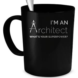 Op de afbeelding: Zwarte koffiemok met een wit ontwerp van een kompas en de tekst "Ik ben een architect. Wat is jouw superkracht?"