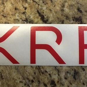 May include: Red vinyl sticker with the word "XRP" in a bold, sans-serif font.