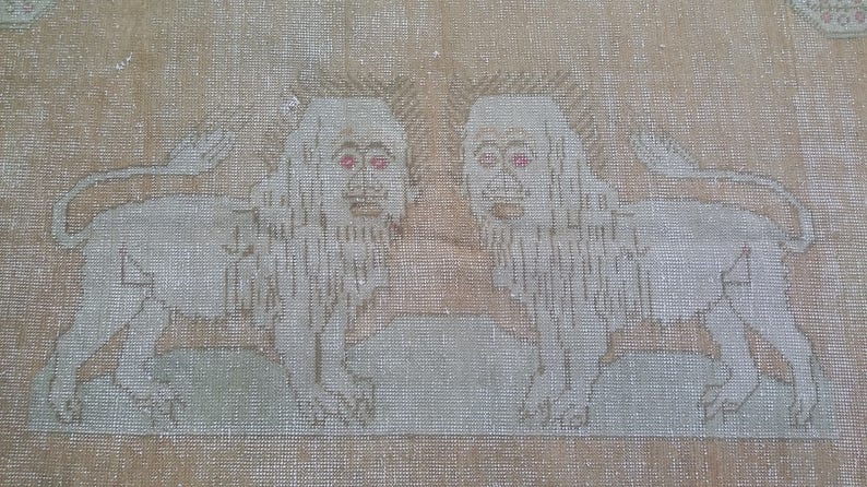 以下が含まれることがあります： ベージュの敷物に、赤い目をした白いライオンが2匹刺繍されている