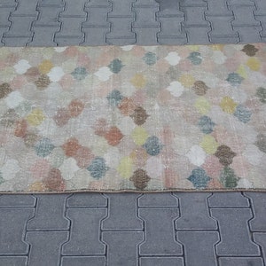 May include: Rectangular rug with a repeating quatrefoil pattern in pastel colors. The rug features a beige background with colorful quatrefoils in shades of pink, blue, yellow, and brown. The rug has a distressed, vintage look.